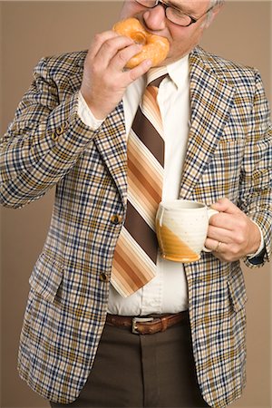 Homme d'affaires rétro manger un beignet et boire une tasse de café Photographie de stock - Premium Libres de Droits, Code: 600-02757029