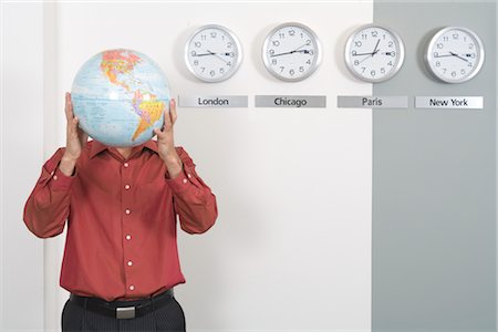 Businessman Holding Globe Standing by Clocks Showing International Time Zones Foto de stock - Sin royalties Premium, Código: 600-02757037