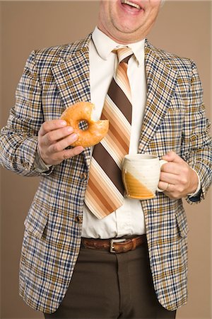 Retro Businessman Eating a Doughnut and Drinking a Cup of Coffee Stock Photo - Premium Royalty-Free, Code: 600-02757030