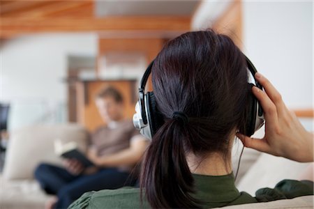 Back View of Woman Wearing Headphones, Man Reading in the Background Foto de stock - Sin royalties Premium, Código: 600-02757337