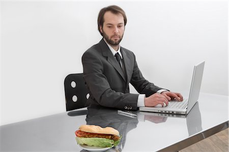 simsearch:6109-06195339,k - Homme d'affaires un Sandwich en regardant sur son bureau Photographie de stock - Premium Libres de Droits, Code: 600-02798118