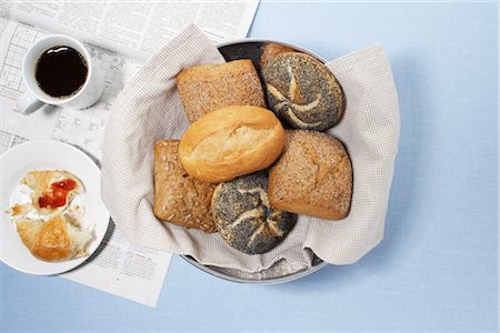 Assortment of Bread Rolls with Newspaper, Cup of Coffee, and Half-Eaten Croissant Stock Photo - Premium Royalty-Free, Code: 600-02801103