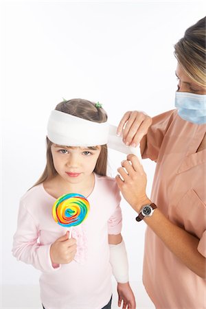 Infirmière enveloppant le Bandage autour de la tête de la jeune fille Photographie de stock - Premium Libres de Droits, Code: 600-02912824
