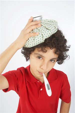 Boy With a Thermometer in His Mouth and an Ice Pack on His Head Foto de stock - Royalty Free Premium, Número: 600-02912845