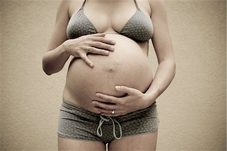 pregnant woman in swimsuit - Woman, Nine Months Pregnant, Touching Her Belly Stock Photo - Premium Royalty-Free, Code: 600-02922770