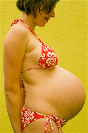 Pregnant woman in bra and panties touching stomach - Stock Image