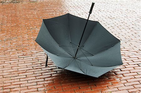 Open Umbrella Lying on Wet Cobblestones Stock Photo - Premium Royalty-Free, Code: 600-03003924