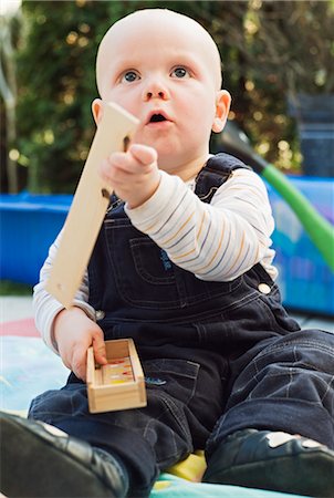 Boy Sitting in Backyard, Playing with Wooden Building Blocks Foto de stock - Sin royalties Premium, Código: 600-03152394