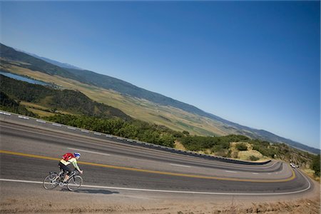 Woman Riding Her Bicycle Down a Hill Toward Steamboat Springs, Routt County, Colorado, USA Stock Photo - Premium Royalty-Free, Code: 600-03210484