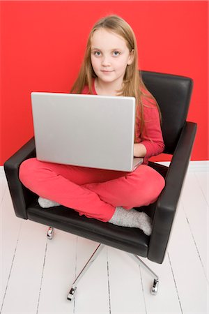 Portrait of Girl Sitting in Chair using Laptop Computer Stock Photo - Premium Royalty-Free, Code: 600-03240862