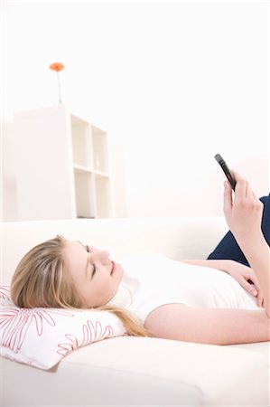 Woman Lying Down Using Cell Phone Stock Photo - Premium Royalty-Free, Code: 600-03404084