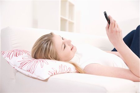 phone young caucasian woman relaxed - Woman Lying Down Using Cell Phone Stock Photo - Premium Royalty-Free, Code: 600-03404085