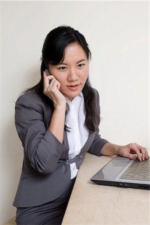 simsearch:6102-07768380,k - Businesswoman Using Laptop Computer and Talking on Cell Phone Fotografie stock - Premium Royalty-Free, Codice: 600-03404104