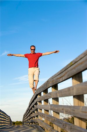 Man Balancing on Wooden Railing, Honeymoon Island, Florida, USA Stock Photo - Premium Royalty-Free, Code: 600-03439272