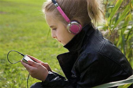 Young Girl Sitting Outside Listening to Music Foto de stock - Royalty Free Premium, Número: 600-03641029