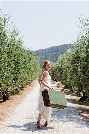 suitcase for italy - Bride carrying suitcase on country road Stock Photo - Premium Royalty-Free, Code: 614-05399399