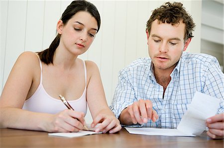 Couple planning home finances, woman writing cheque Stock Photo - Premium Royalty-Free, Code: 614-05399668