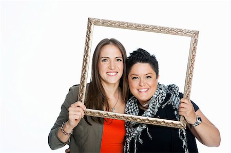 person holding picture frame - Lesbian couple holding picture frame against white background Stock Photo - Premium Royalty-Free, Code: 614-05523010