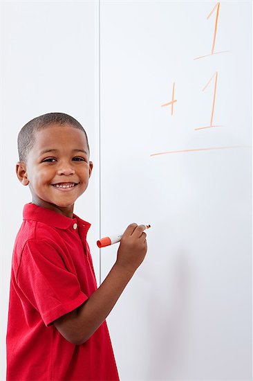 Boy with sum on whiteboard Stock Photo - Premium Royalty-Free, Image code: 614-05523126