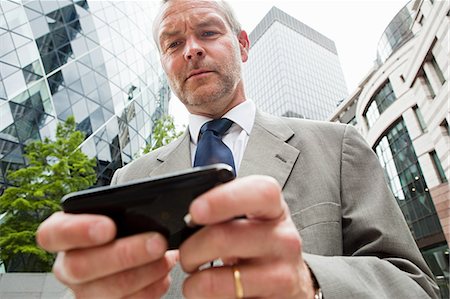 swiss re tower - Businessman using smartphone and the go Stock Photo - Premium Royalty-Free, Code: 614-05556713