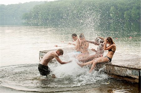 people standing on docks - Mid adult man splashing friends in lake Stock Photo - Premium Royalty-Free, Code: 614-05556833