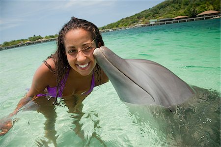roatan - Young woman smiling with dolphin in sea Foto de stock - Royalty Free Premium, Número: 614-05556892