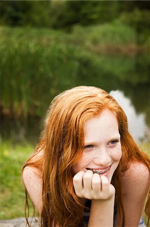 Teenage girl smiling at friends with a lake behind her Fotografie stock - Premium Royalty-Free, Codice: 614-05557012