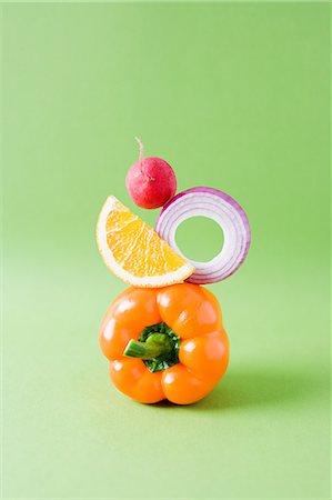 stacked vegetables - Arrangement of pepper, onion, orange and radish against green background Stock Photo - Premium Royalty-Free, Code: 614-05557060