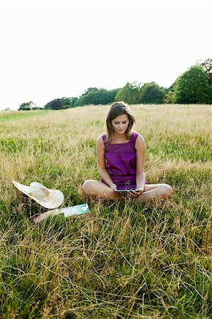 solitario - Young woman using hand held device in the middle of a field Foto de stock - Sin royalties Premium, Código: 614-05557120