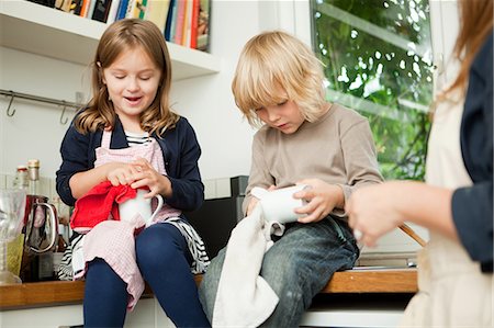 Siblings drying cups on kitchen counter Stock Photo - Premium Royalty-Free, Code: 614-05557422