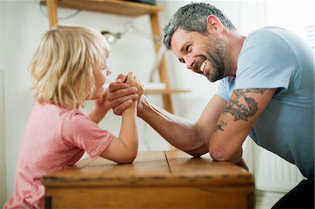 Mid adult man arm wrestling with son Foto de stock - Sin royalties Premium, Código: 614-05557439