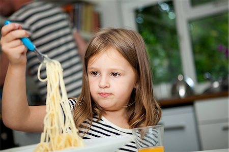 spaghetti - Girl holding up spaghetti at table Stock Photo - Premium Royalty-Free, Code: 614-05557431