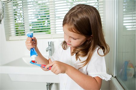 Girl applying toothpaste to brush in bathroom Stock Photo - Premium Royalty-Free, Code: 614-05557433