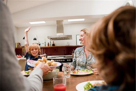 Family at the dinner table with son raising arm requesting more food Stock Photo - Premium Royalty-Free, Code: 614-05650642