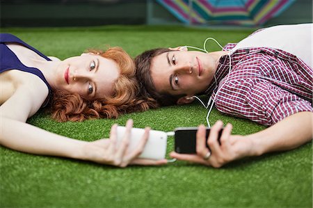 earphone sharing - Couple lying down looking at mobile phones Stock Photo - Premium Royalty-Free, Code: 614-05650682