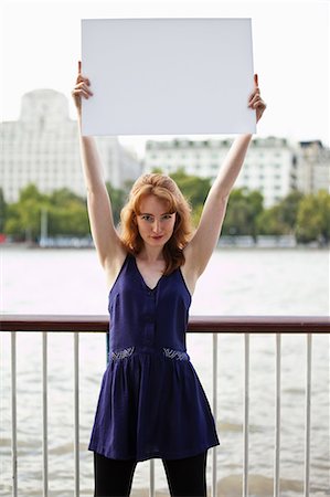 Young woman holding up a white message board Stock Photo - Premium Royalty-Free, Code: 614-05650691