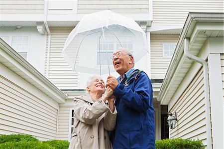 standing in the rain photography - Senior couple holding umbrella outside Stock Photo - Premium Royalty-Free, Code: 614-05650723