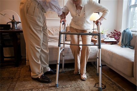 Senior man assisting wife with walking frame at home Stock Photo - Premium Royalty-Free, Code: 614-05650734