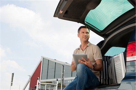 Man using data tablet in airport carpark Stock Photo - Premium Royalty-Free, Code: 614-05650827