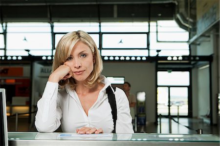 sad adult looking at camera - Bored woman at check in desk of airport Stock Photo - Premium Royalty-Free, Code: 614-05650833