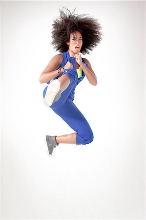 empowered - Young woman kicking in mid air Stock Photo - Premium Royalty-Free, Code: 614-05650910