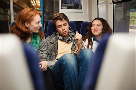 Three young friends travelling on train listening to music Stock Photo - Premium Royalty-Free, Code: 614-05662216