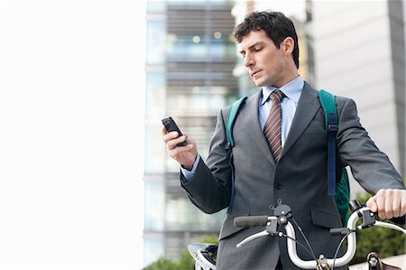 smart phone travel - Mid adult businessman with bike using cellphone Stock Photo - Premium Royalty-Free, Code: 614-05662308