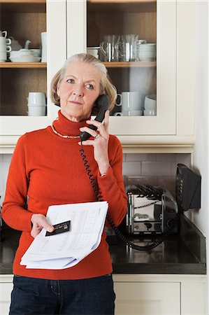Senior woman on telephone with statement and credit card Stock Photo - Premium Royalty-Free, Code: 614-05792320