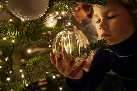 Boy decorating Christmas tree with baubles at home Foto de stock - Sin royalties Premium, Código: 614-05792381