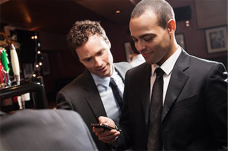 después del trabajo - Businessmen looking at smartphone in bar Foto de stock - Sin royalties Premium, Código: 614-05792407