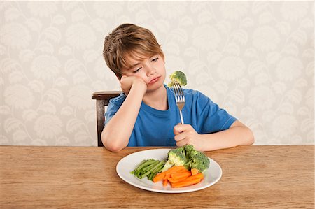 sad young boy - Boy frowning at vegetables Stock Photo - Premium Royalty-Free, Code: 614-05818925