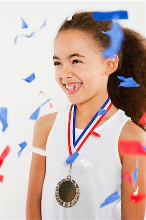 Girl wearing medal with ticker tape falling Stock Photo - Premium Royalty-Free, Code: 614-05818956