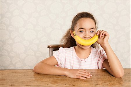 Girl holding a banana over her mouth Foto de stock - Royalty Free Premium, Número: 614-05818952