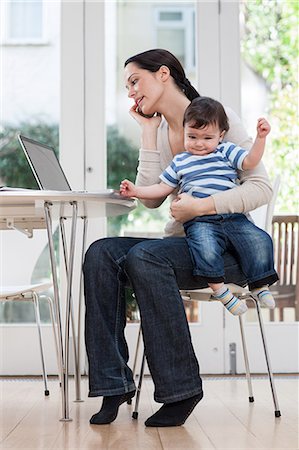 sad adult looking at camera - Mother holding baby boy, using cellphone and laptop Stock Photo - Premium Royalty-Free, Code: 614-05955639